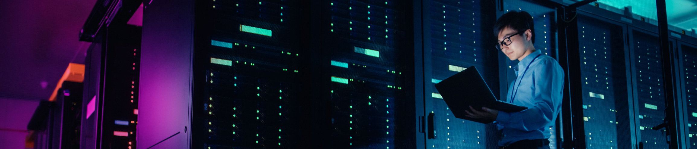an engineer looking at his computer in a server room