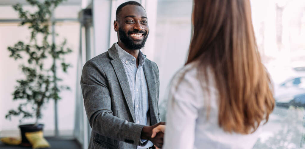 a man smiling shaking the hand of a woman