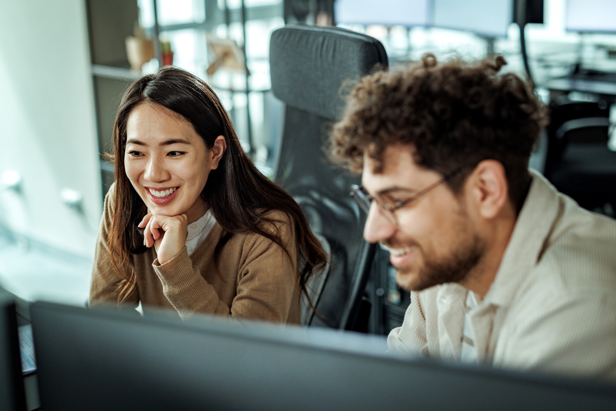 a man and woman looking at computer monitors