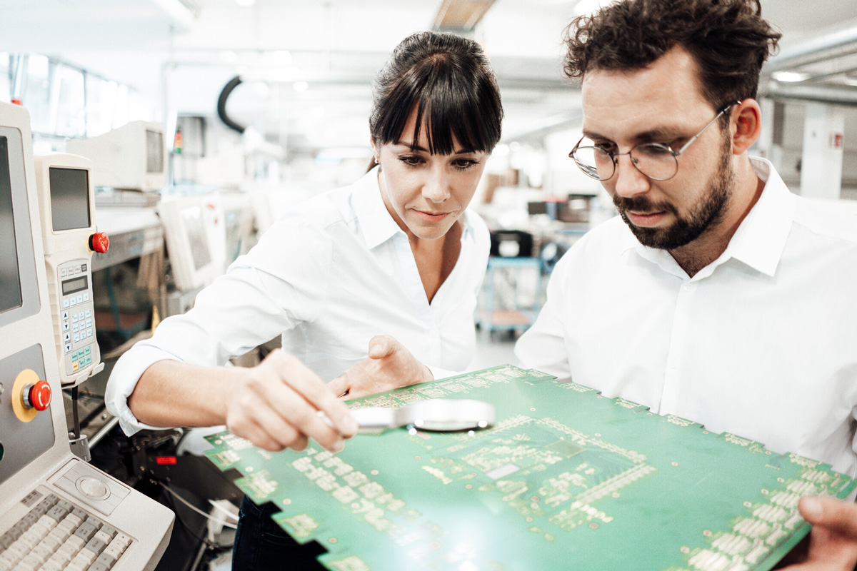 a man and woman looking at a circuit board